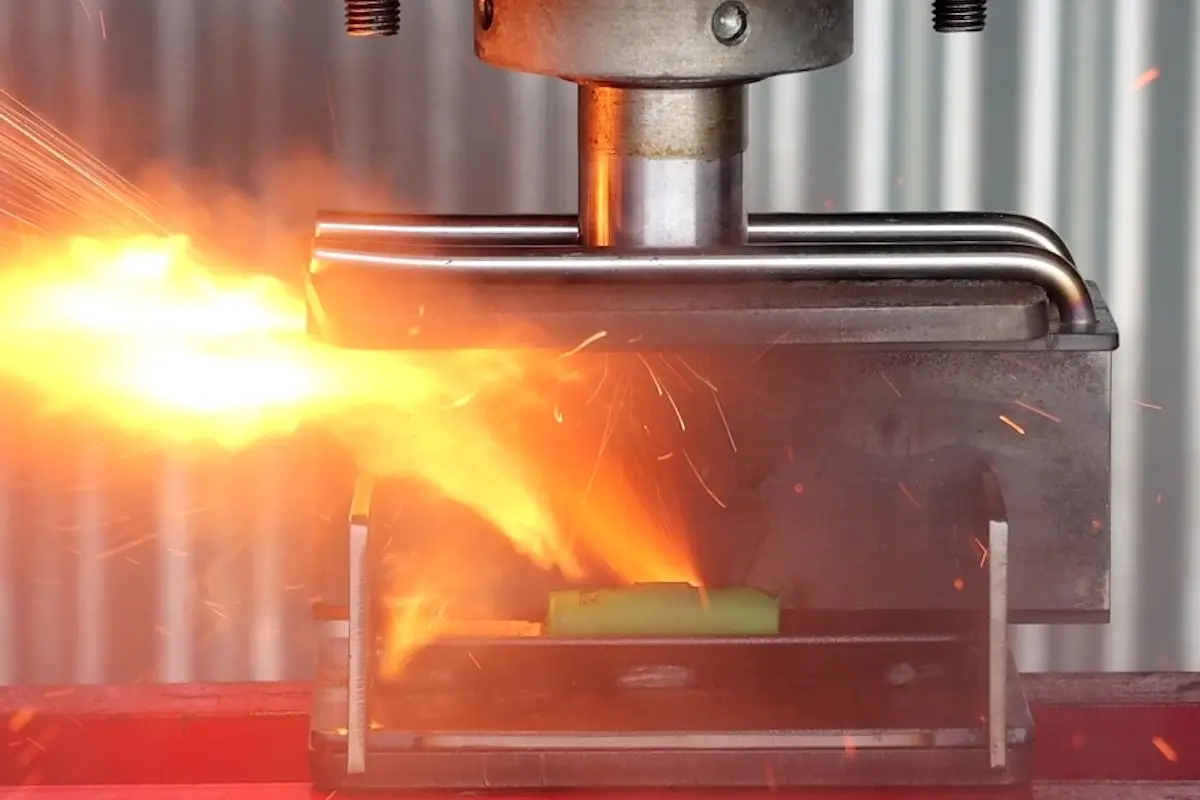 Battery cell undergoing a crush test, representing battery safety and abuse testing under extreme mechanical conditions.